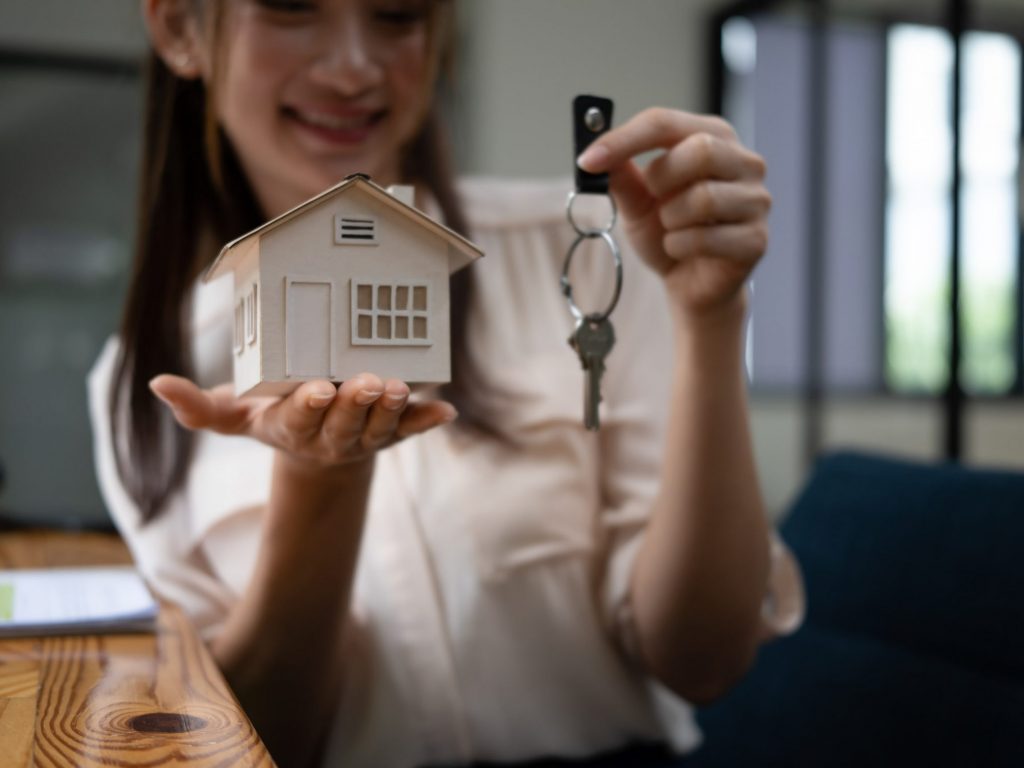 young-woman-holding-house-model-and-key-real-esta-2022-03-09-02-56-18-utc-scaled-1024x768